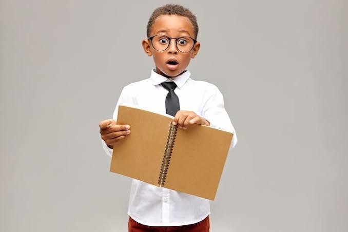 Garçon à lunettes en chemise et cravate, l’air surpris, un cahier ouvert