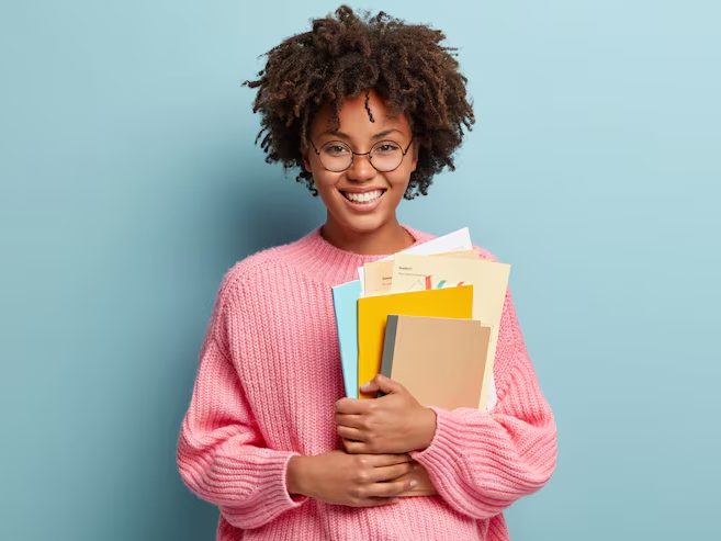 Jeune femme souriante tenant des cahiers colorés