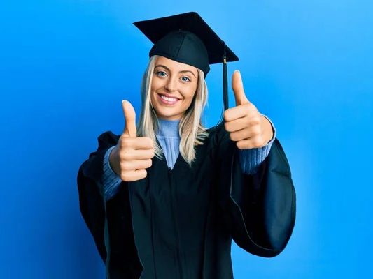 Jeune diplômée souriante, pouce levé