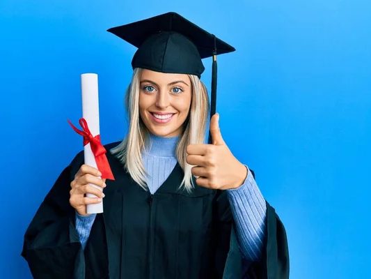 Jeune diplômée souriante tenant son diplôme, pouce levé