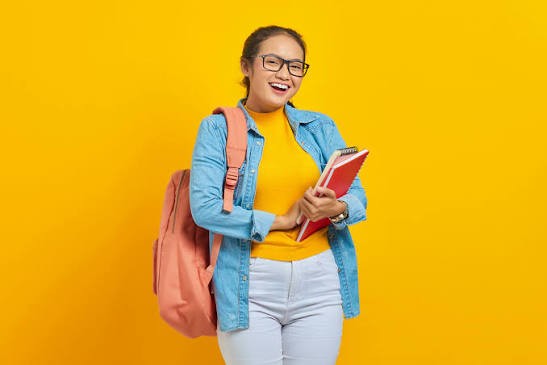 Étudiante riant aux éclats, un cahier rouge dans les bras