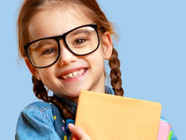 Jeune fille souriante avec des lunettes tenant des cahiers colorés