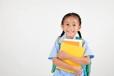 Petite fille souriante aux couettes, des cahiers dans les bras